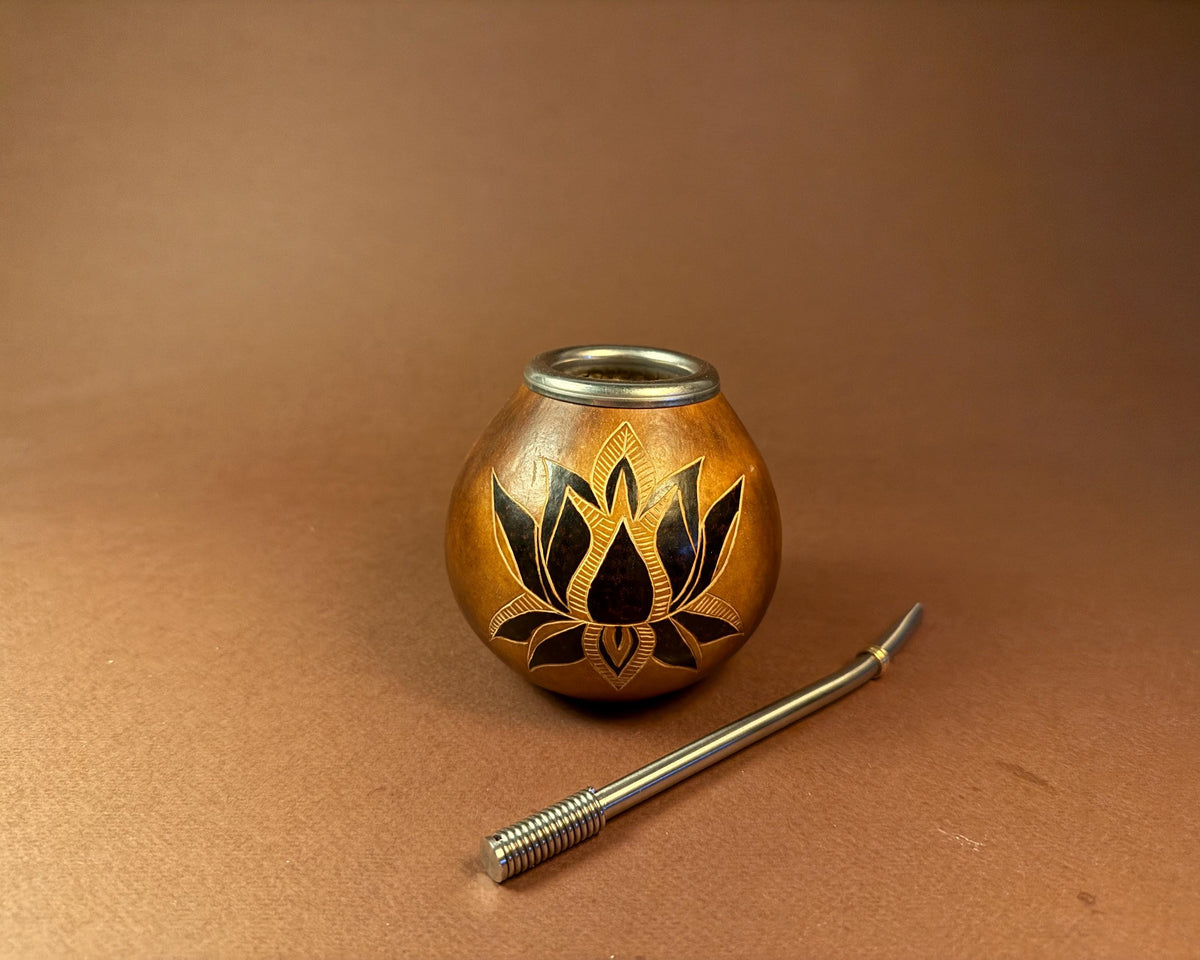 A small round wooden goblet or teapot with a carved lotus design, shown with a metal straw on a brown background.